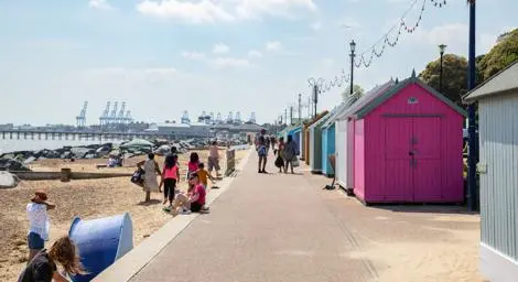 Felixstowe seafront with people walking and colourful beach huts on a summer day