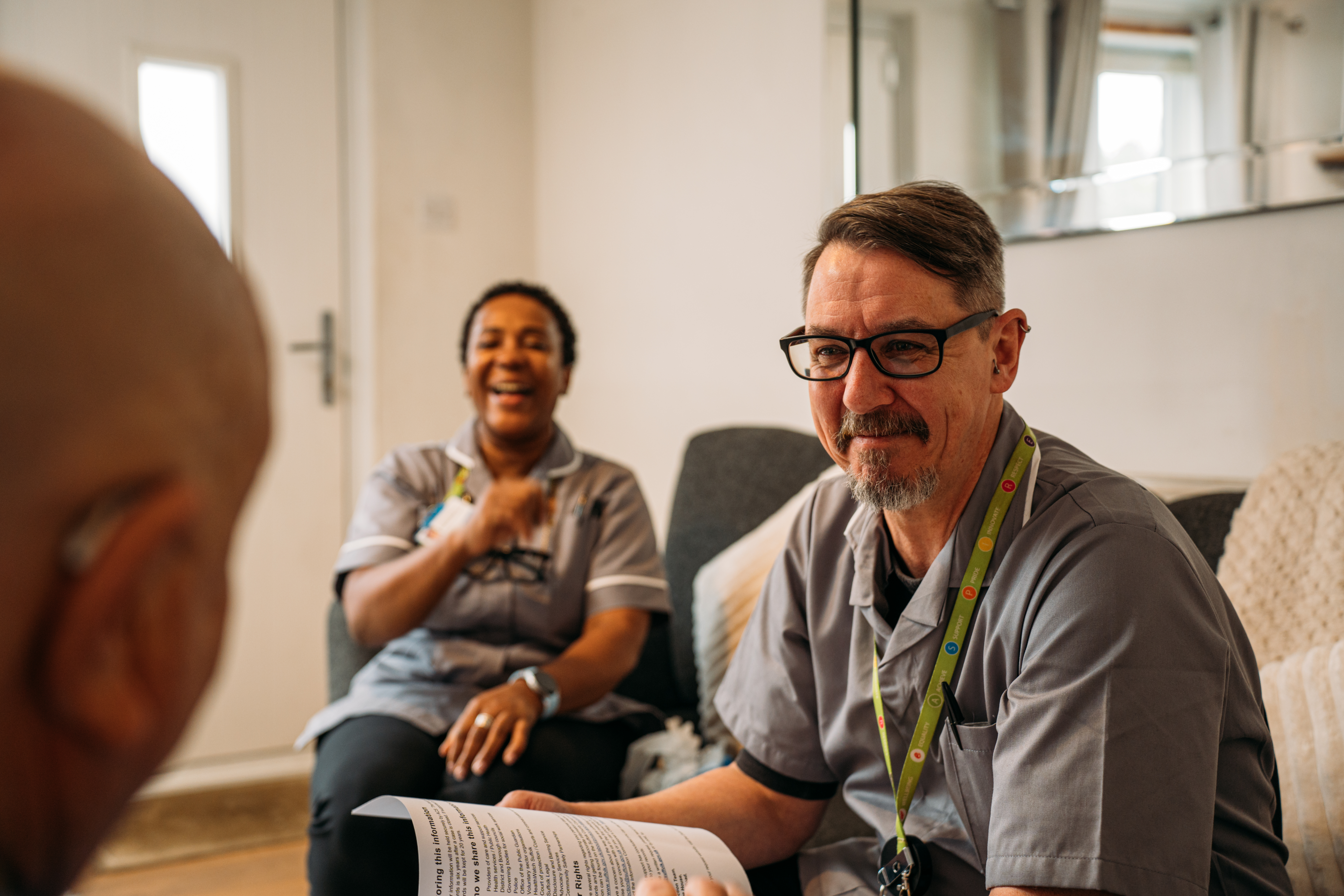 Two Home First carers in Suffolk sitting with a person on a sofa at home