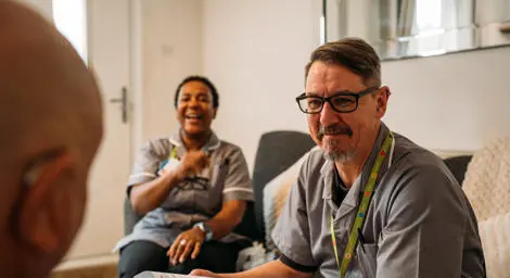 Two Home First carers in Suffolk sitting with a person on a sofa at home